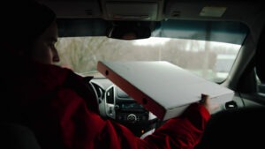 A,delivery,man,drives,a,car,and,holding,a,pizza