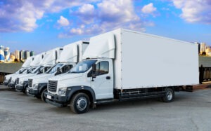 Some,trucks,are,parked,in,a,parking,lot,next,to