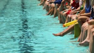 Muchas personas sentadas en el borde de una piscina. Póngase en contacto con un abogado de accidentes por ahogamiento en Texas si un ser querido sufrió un accidente en una piscina o lago.