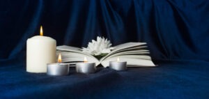 Candle and flowers placed near book memorialize deceased family member after car accident