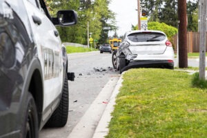 Police car near car with rear end damage on side of road