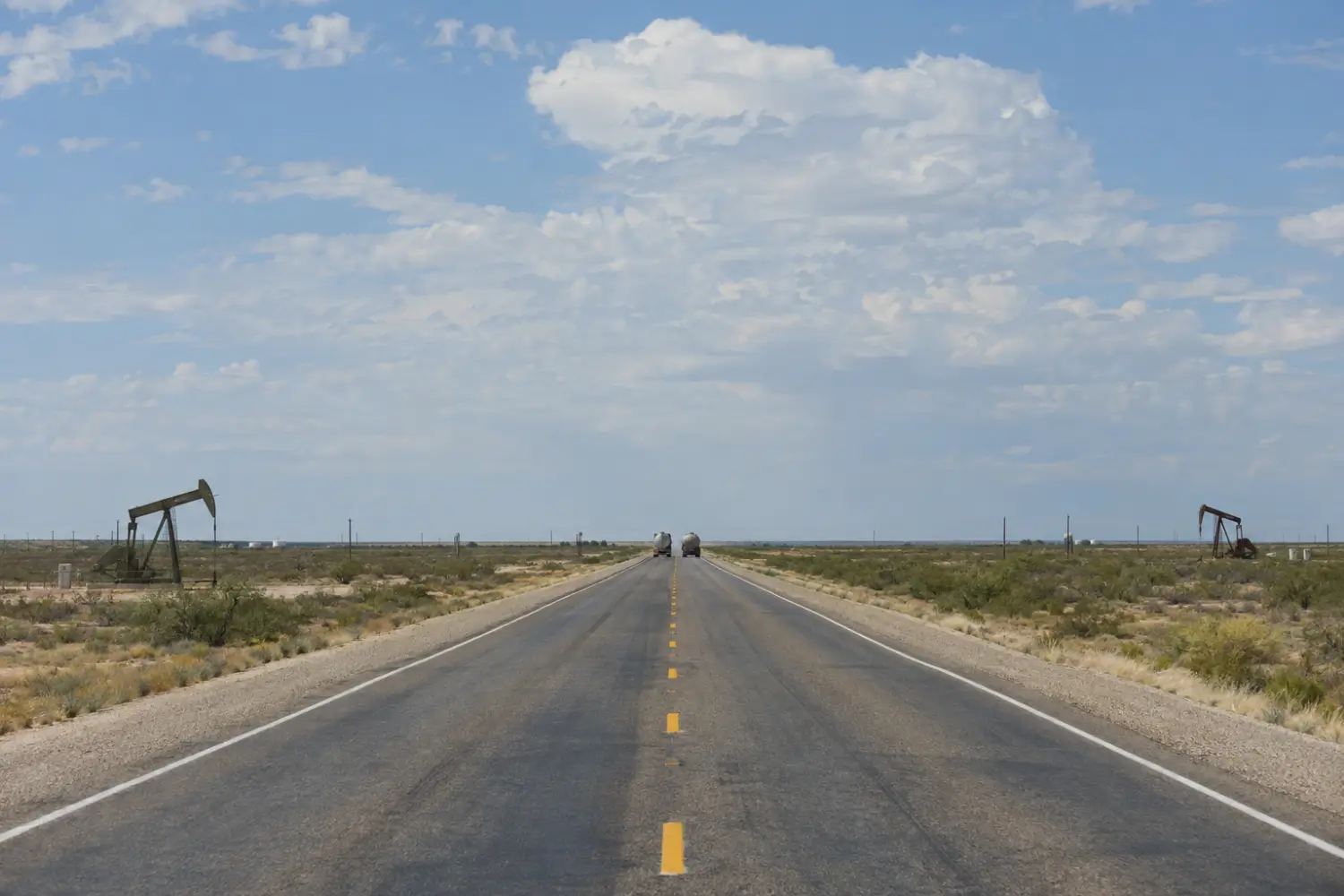 Highway through the Permian Basin with tanker trucks in the distance