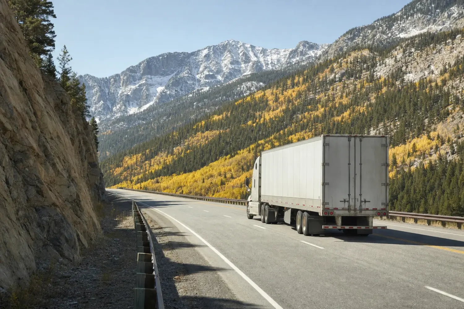 Tractor-trailer on an interstate climbing past golden aspen groves and evergreens under snow-dusted peaks