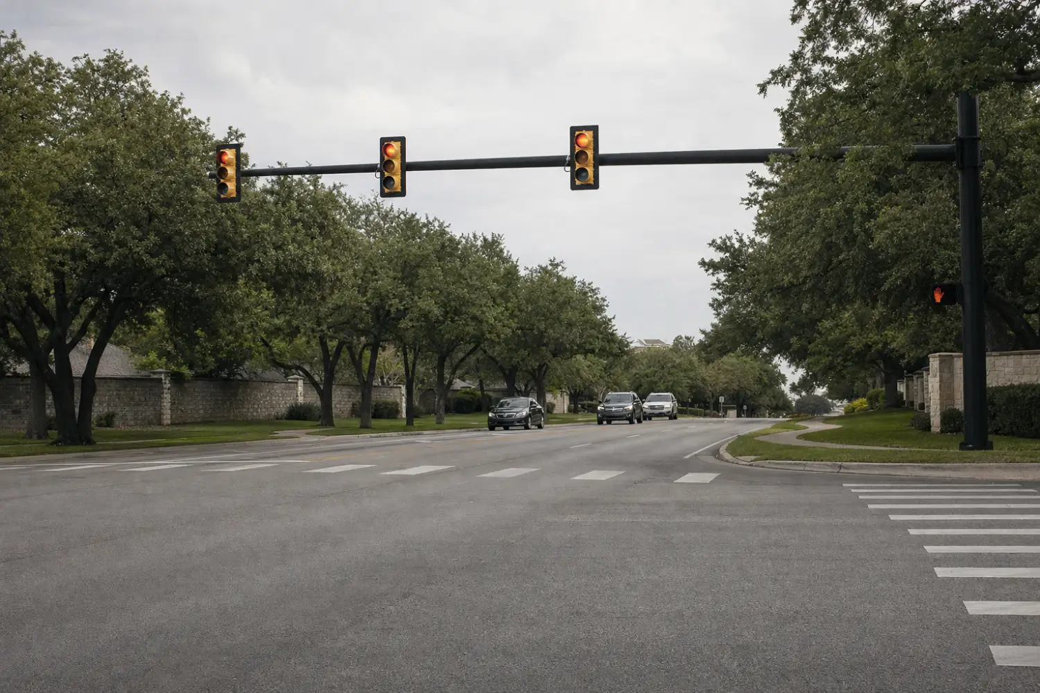 Signalized suburban intersection with an empty crosswalk and live oak trees along the street